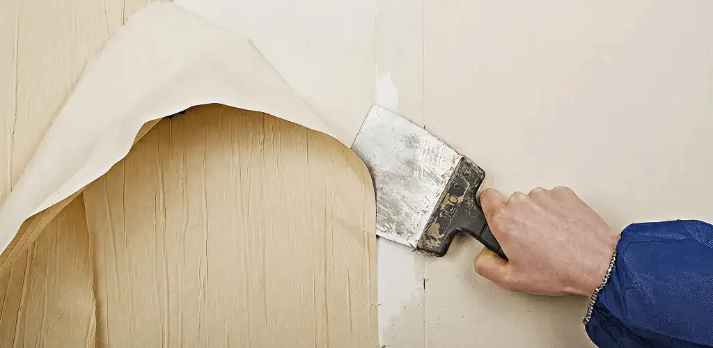 Handyman removing wallpaper with a scraper for wall preparation in Provo, UT