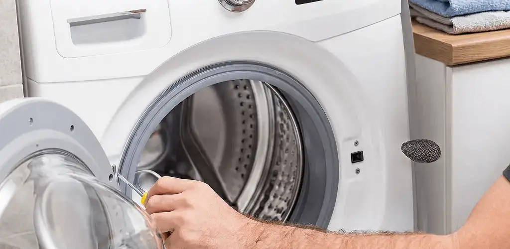 Handyman repairing a front-load washing machine and inspecting the drum in Provo, UT