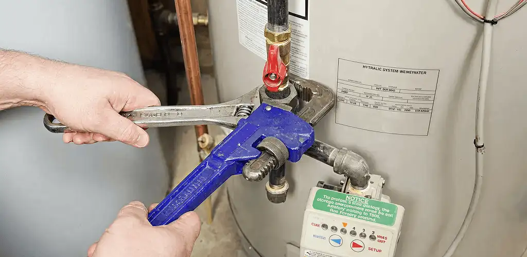 Water heater repair technician tightening the shutoff valve and supply line in Provo, UT